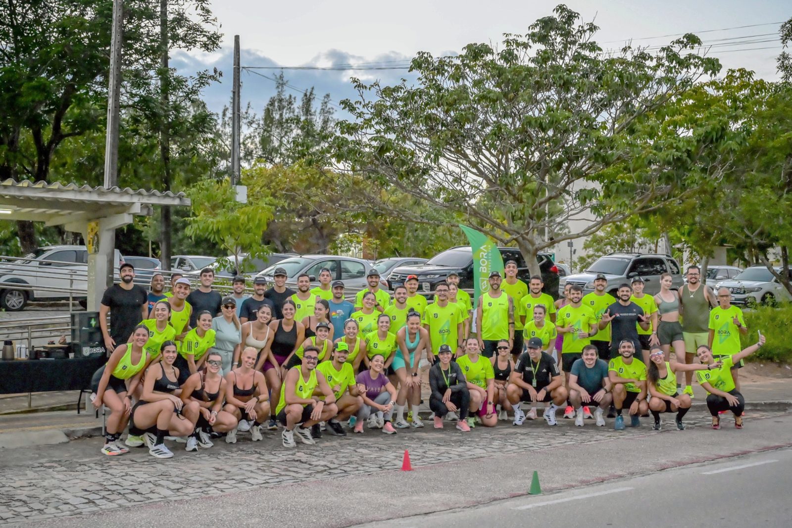 Turma da BORA Natal reunida na rua antes do treino, com a bandeira da BORA ao fundo